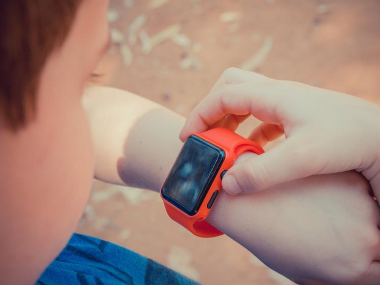 Ein Kind bedient eine Smartwatch. 