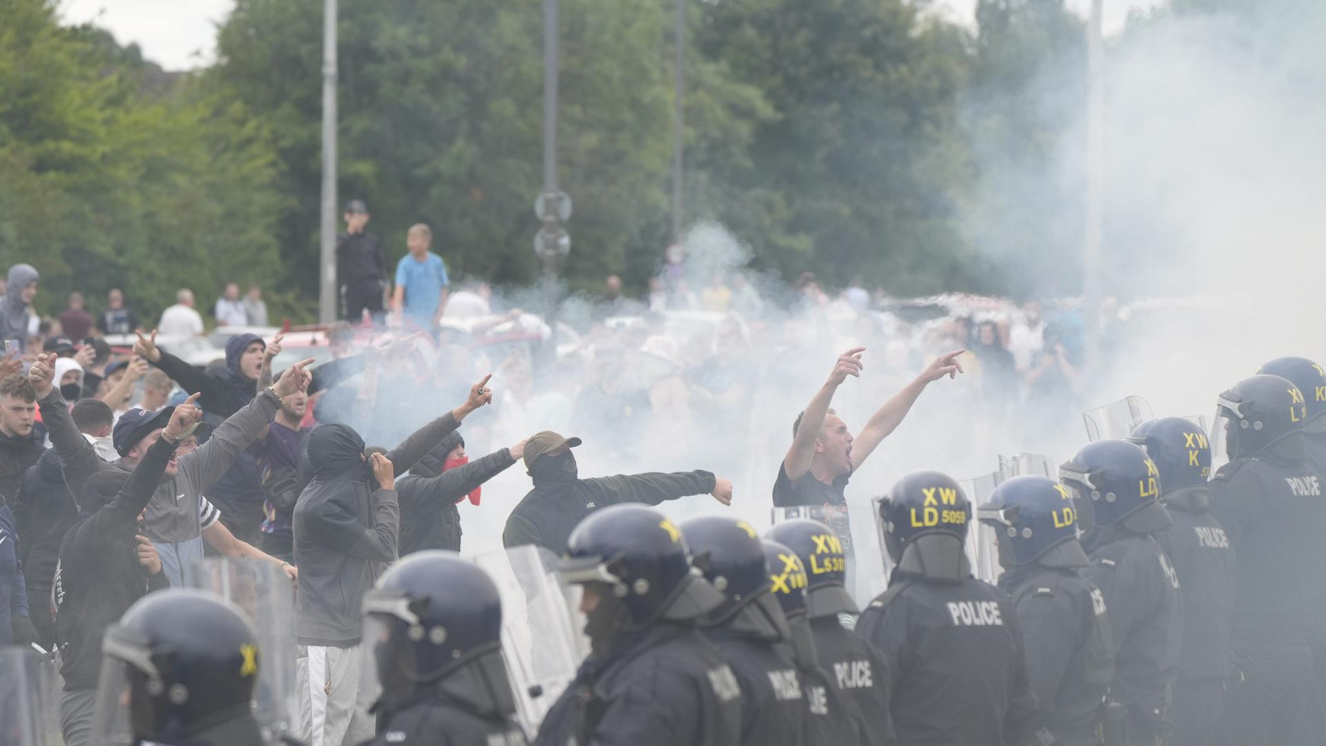 Polizeibeamte stehen brüllenden Demonstranten während einer Demonstration gegen Einwanderung vor dem Holiday Inn Express in Rotherham, South Yorkshire, gegenüber. 