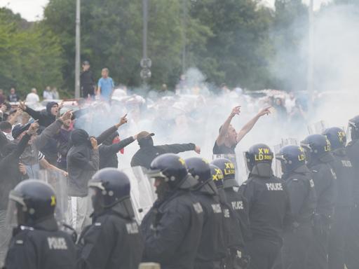 Polizeibeamte stehen brüllenden Demonstranten während einer Demonstration gegen Einwanderung vor dem Holiday Inn Express in Rotherham, South Yorkshire, gegenüber. 