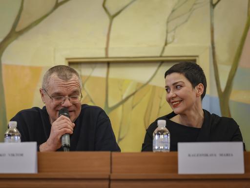 Auf einer Pressekonferenz am 14.12.2025 schaut Maria Kolesnikowa lächelnd zu ihrem Sitznachbar Viktor Babariko, der in ein Mikro spricht Auf einer Pressekonferenz am 14.12.2025 schaut Maria Kolesnikowa lächelnd zu ihrem Sitznachbar Viktor Babariko, der in ein Mikro spricht