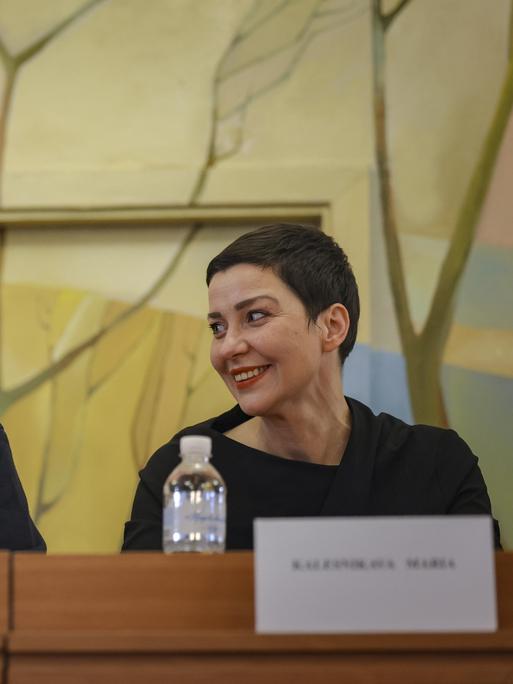 Auf einer Pressekonferenz am 14.12.2025 schaut Maria Kolesnikowa lächelnd zu ihrem Sitznachbar Viktor Babariko, der in ein Mikro spricht Auf einer Pressekonferenz am 14.12.2025 schaut Maria Kolesnikowa lächelnd zu ihrem Sitznachbar Viktor Babariko, der in ein Mikro spricht