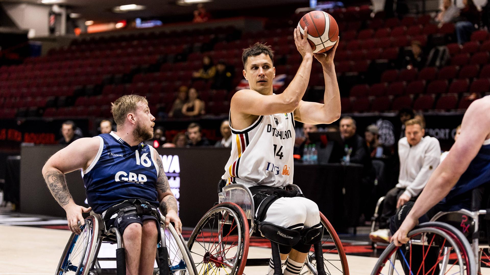 Ein deutscher Rollstuhl-Basketballer hat den Ball in der Hand, ein Gegenspieler ist neben ihm.