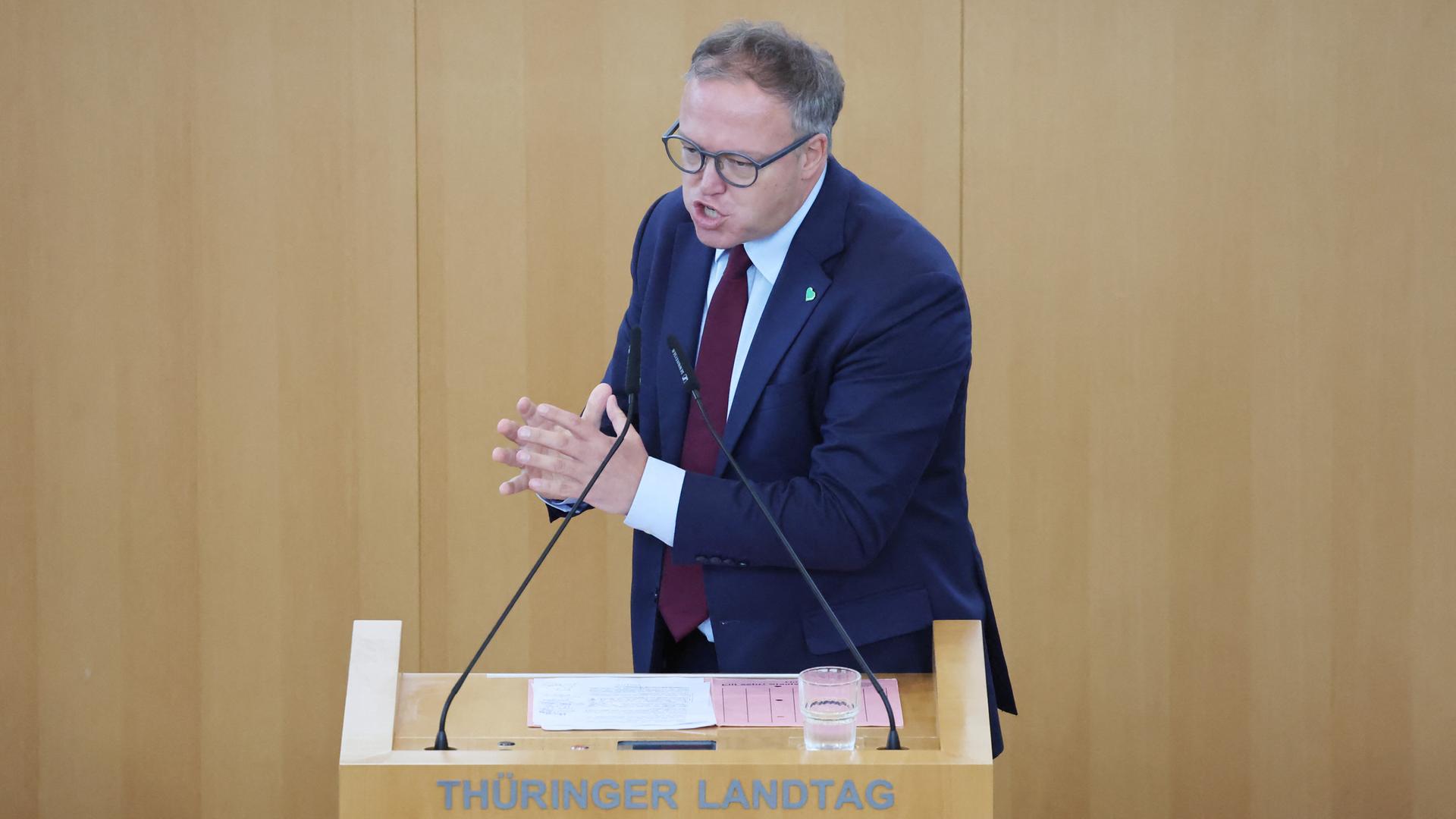 Voigt steht an dem Rede-Pult in dem Landtag und spricht. Er macht mit beiden Händen eine Geste. Voigt steht an dem Rede-Pult in dem Landtag und spricht. Er macht mit beiden Händen eine Geste.