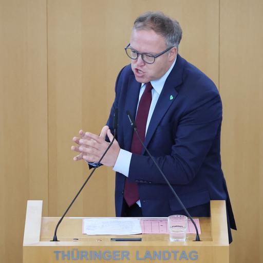 Voigt steht an dem Rede-Pult in dem Landtag und spricht. Er macht mit beiden Händen eine Geste.