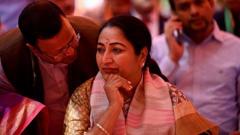 Delhis Ministerpräsidentin Rekha Gupta sitzt das Kinn auf die Hand gestützt in traditionell indischer Kleidung in einer Gruppe von Männern. Jagat Prakash Nadda, Vorsitzender der BJP-Partei, lehnt über ihrer Schulter und spricht ihr ins Ohr.
