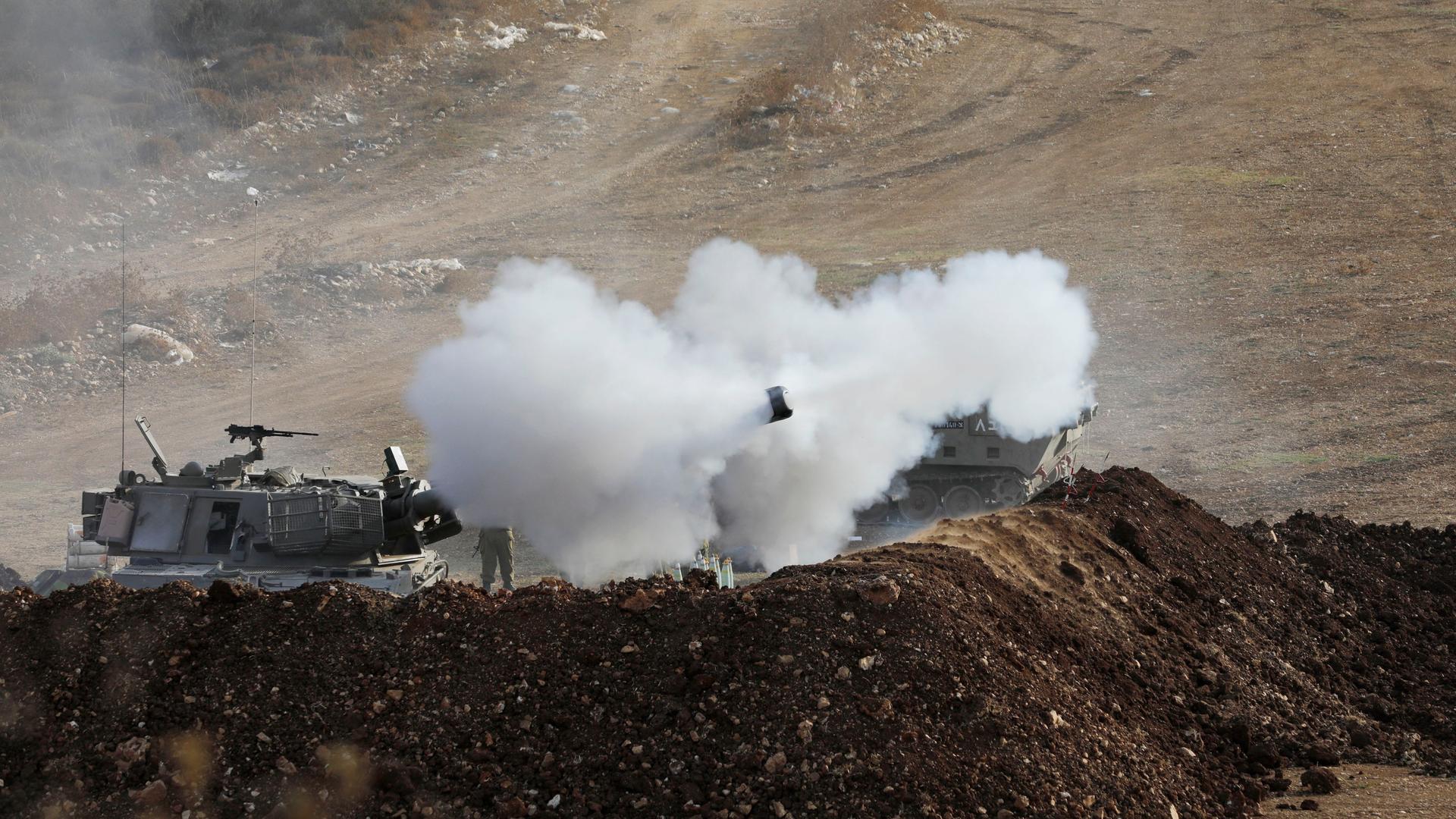 Israelische Soldaten feuern in Richtung Süd-Libanon. Man sieht Rauchwolken und einen Hubschrauber.