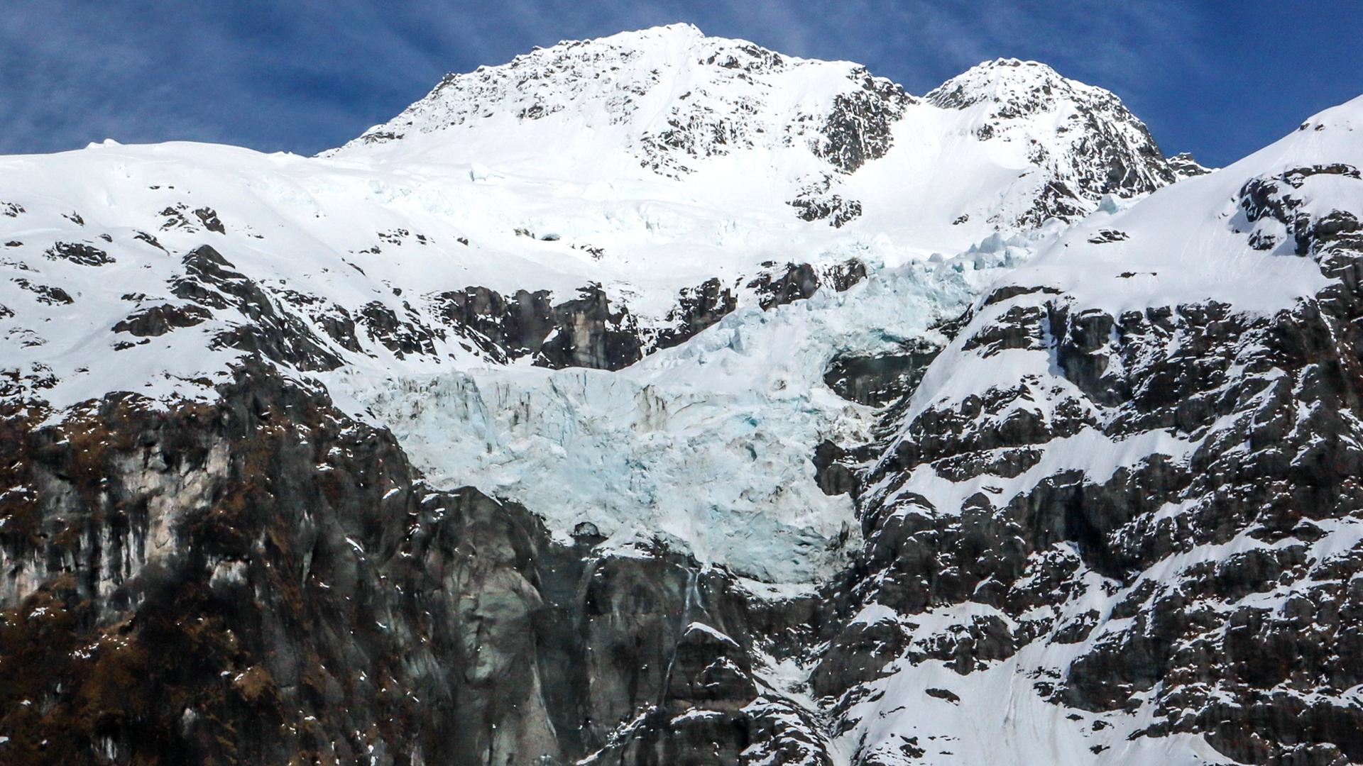 Ein Gletscher liegt zwischen schneebedeckten Bergen im Mount Aspiring National Park in der Nähe von Queenstown auf der Südinsel Neuseelands.