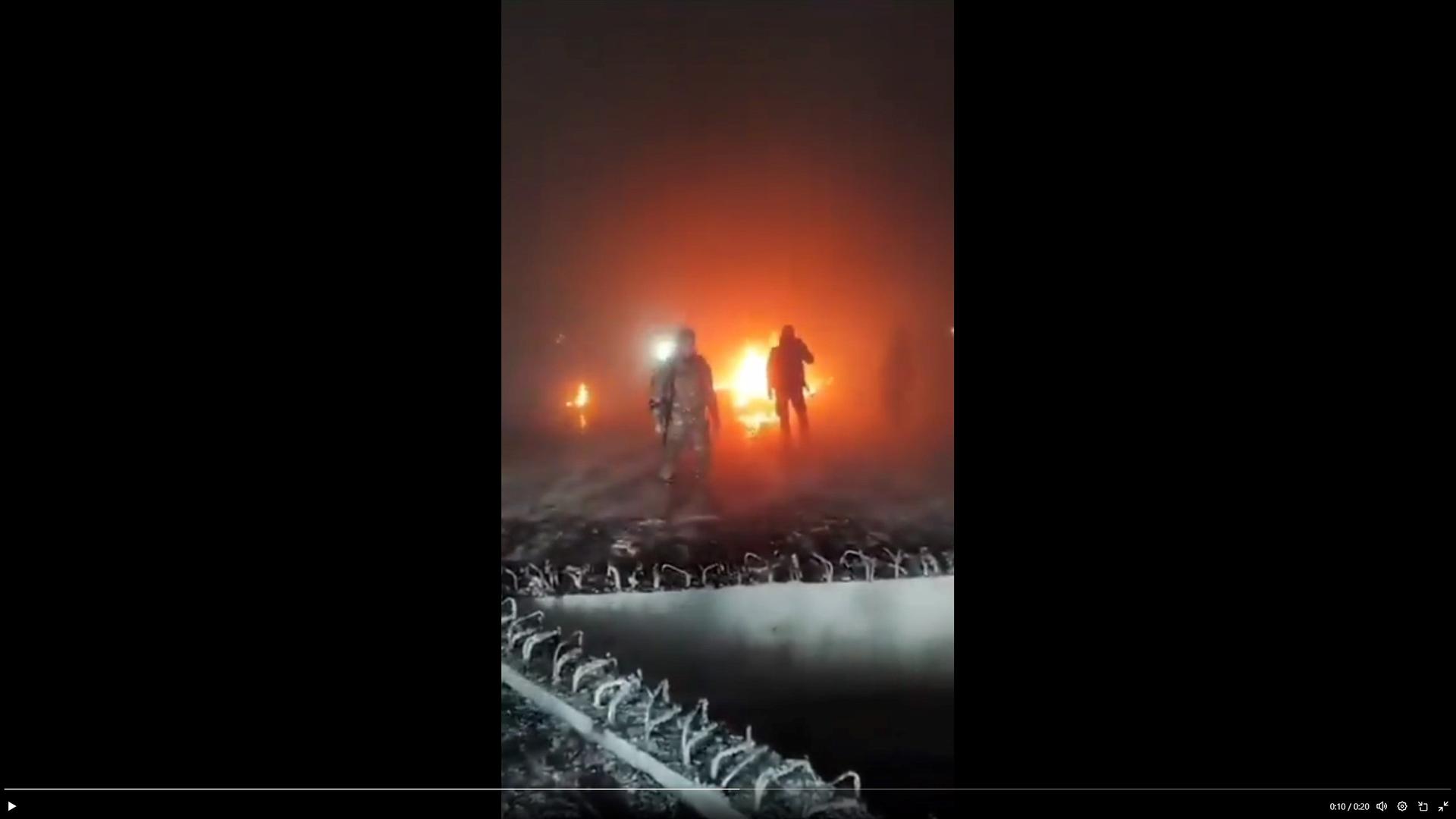 Man sieht verschwommen Menschen, die vor einem Feuer stehen.