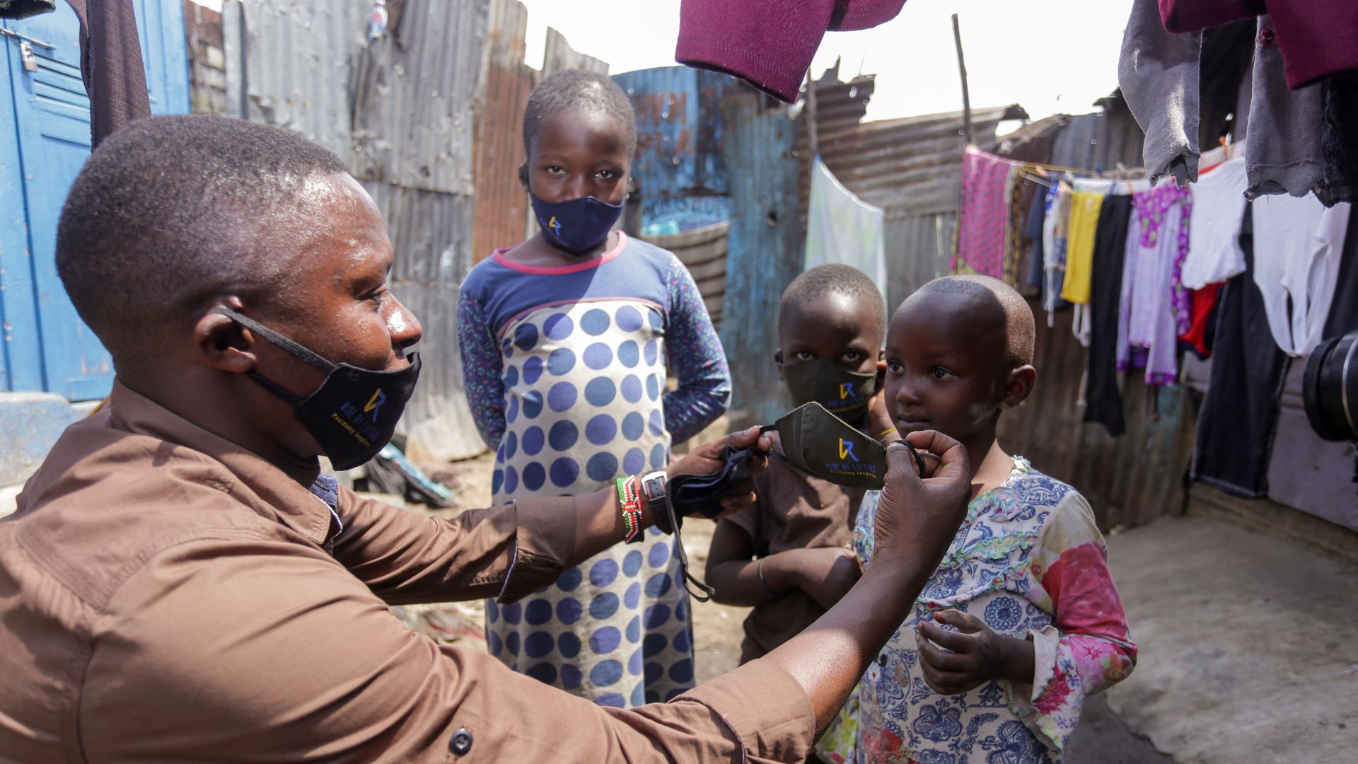 Ein Mann im Mathare-Slum in der kenianischen Hauptstadt Nairobi verteilt Gesichtsmasken an Kinder. 
