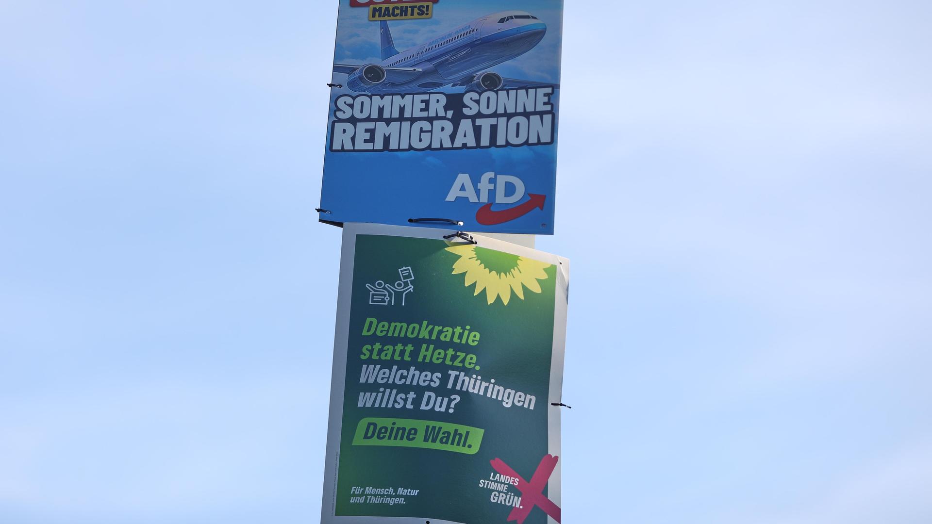 Wahlplakate zur Landtagswahl in Thüringen: Oben: AfD-Wahlplakat mit der Aufschrift "Der Osten machst - Sommer, Sonne, Remigration", darunter Plakat der Grünen mit dem Schriftzug "Demokratie statt Hetze - Welches Thüringen willst du?"