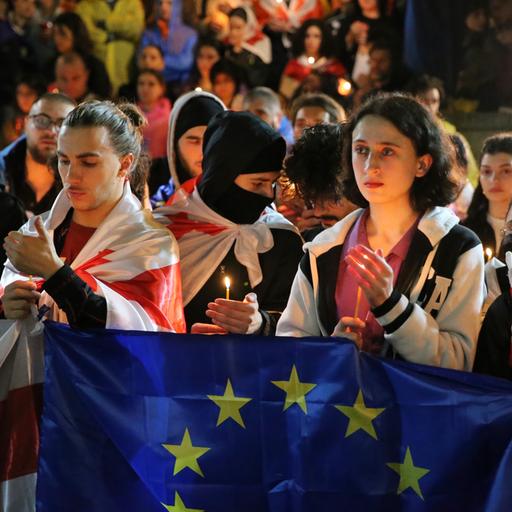 Demonstranten mit georgischen und EU-Fahnen. Sie halten Kerzen in den Händen. 
