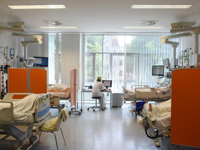 Auf der Intensivtherapie-Station (ITS) im Klinikum St. Georg sitzt eine Mitarbeiterin im Patientenzimmer an einem Computer.