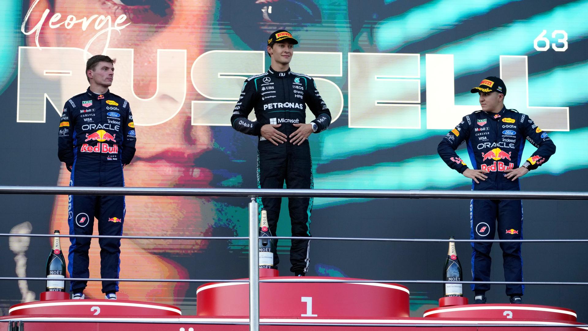 George Russell (m.) nach seinem Sieg in Baku; neben ihm Max Verstappen (l.) und Isack Hadjar (r.) - sie stehen auf dem Sieger-Podest.