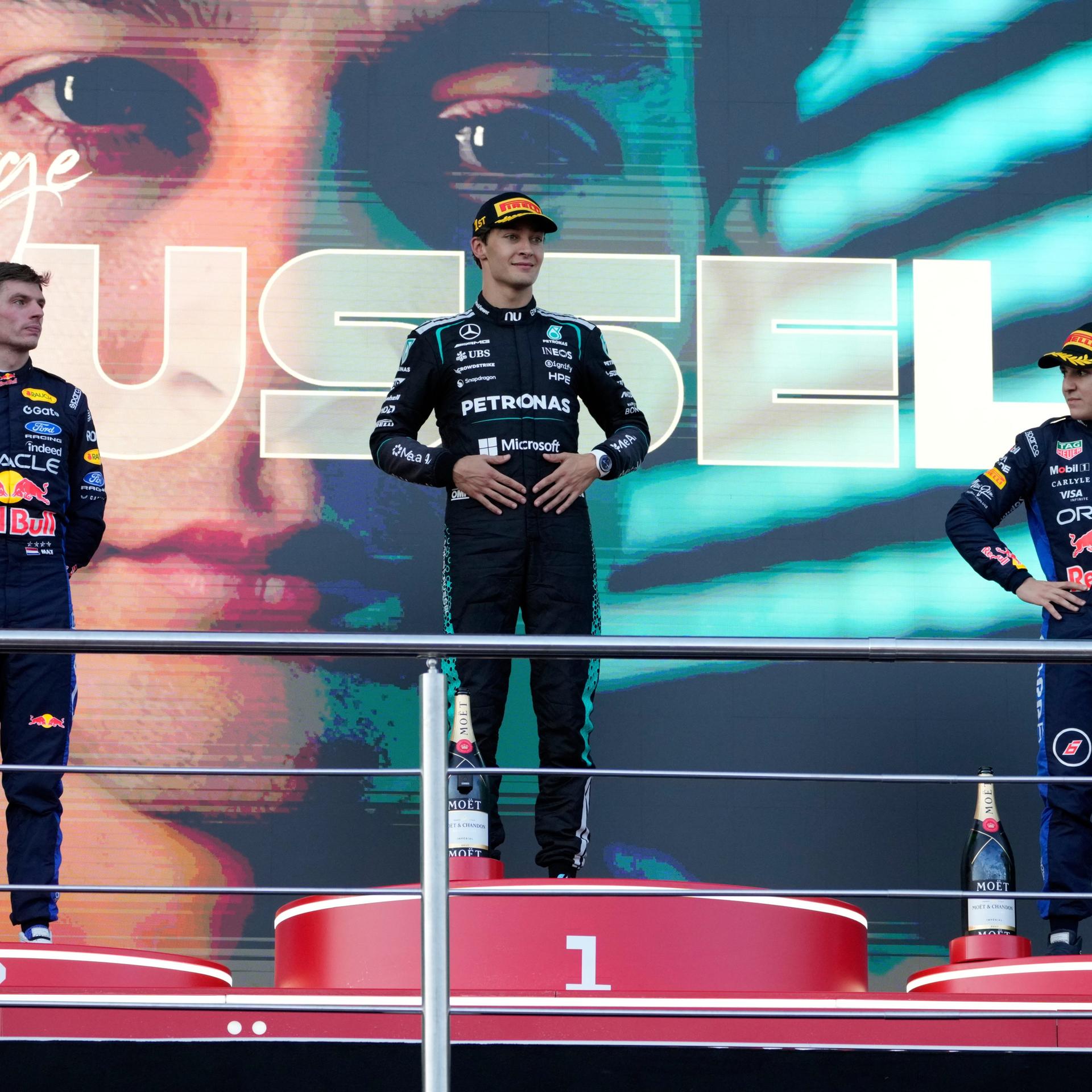 George Russell (m.) nach seinem Sieg in Baku; neben ihm Max Verstappen (l.) und Isack Hadjar (r.) - sie stehen auf dem Sieger-Podest.