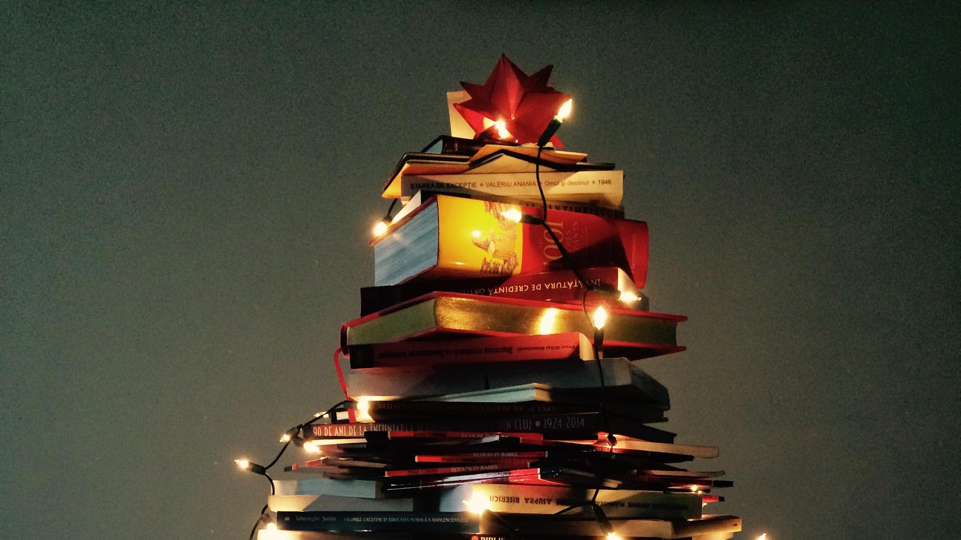Beleuchtete Weihnachtsbeleuchtung auf einem zu einem Weihnachtsbaum geformten Bücherstapel.