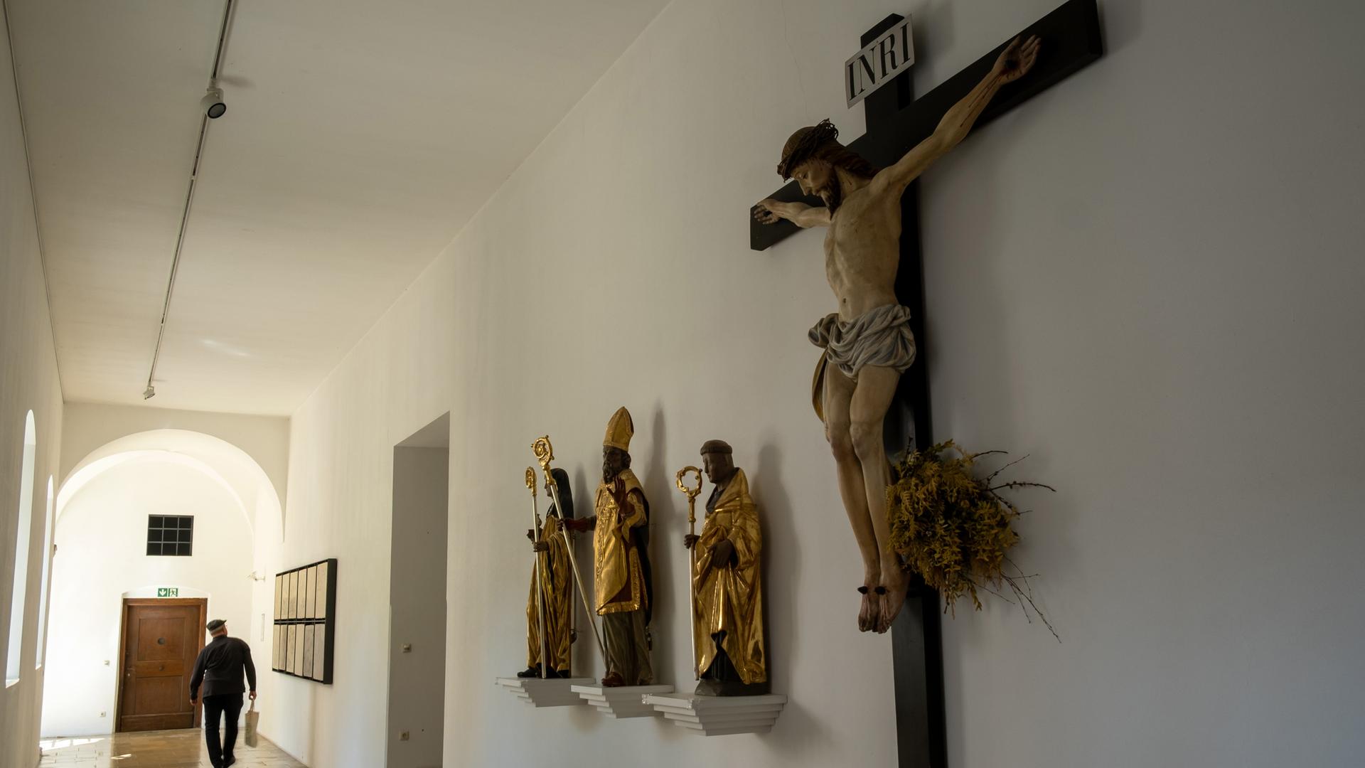 Im Gang eines Priesterseminars sind Statuen und ein Gekreuzigter zu sehen.