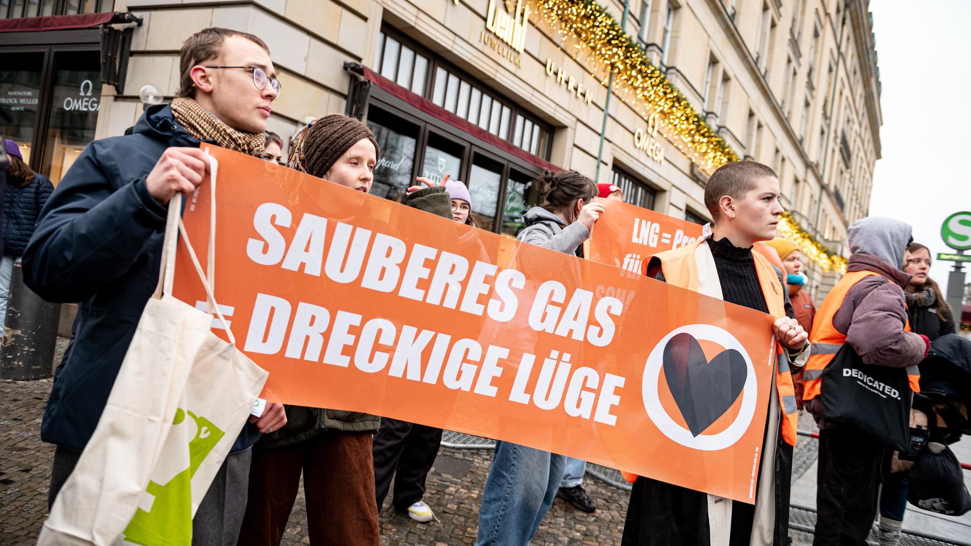 Demonstranten der Letzten Generation stehen vor dem Hotel Adlon in Berlin mit einem Schild mit der Aufschrift "Sauberes Gas = dreckige Lüge". 