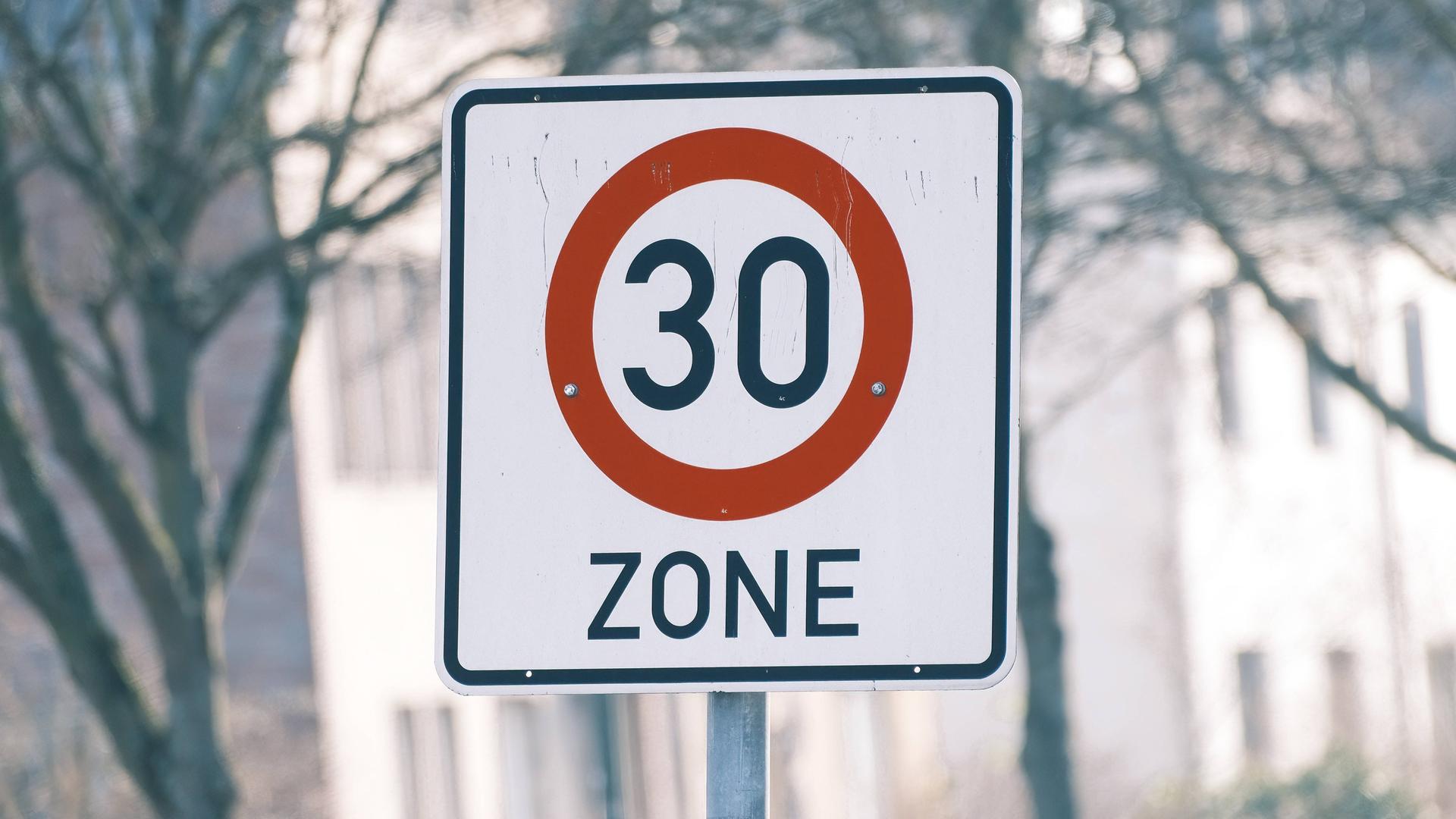 Ein Straßenschild für eine Tempo 30 Zone steht in einem Innenstadtbereich.