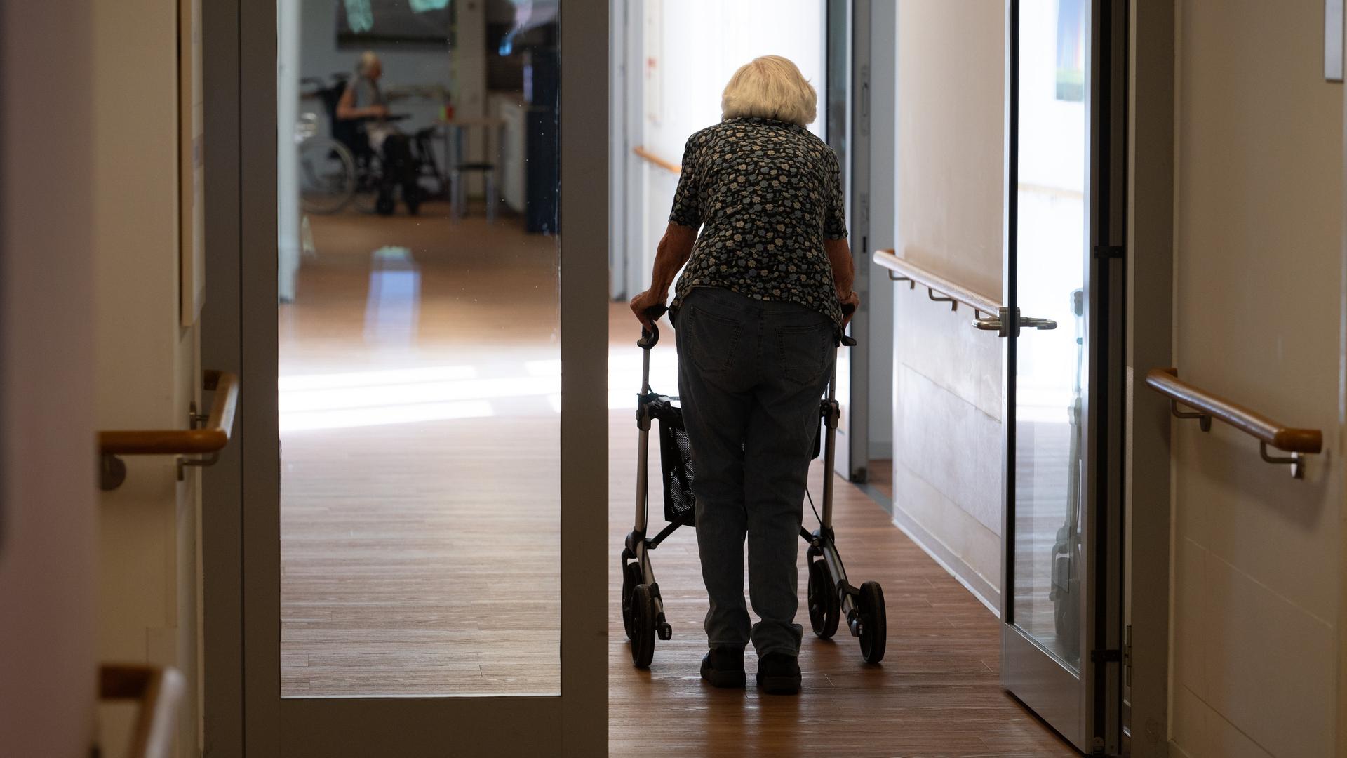 Eine Seniorin mit Rollator geht einen Korridor in einem Pflegeheim entlang, Symbolfoto.