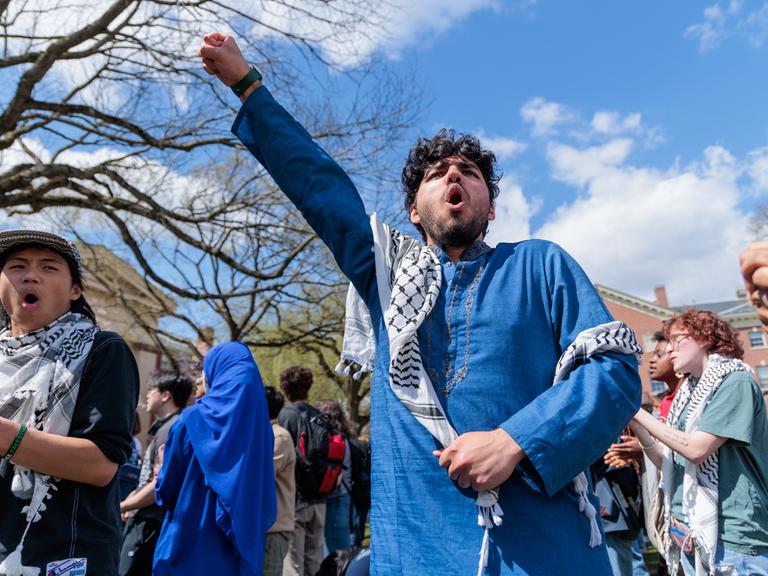 Studierende bei einer Solidaritätskundgebung an der Brown University in Rhode Island am 24.04.2024 mit Palästinensertuch und erhobener Faust.