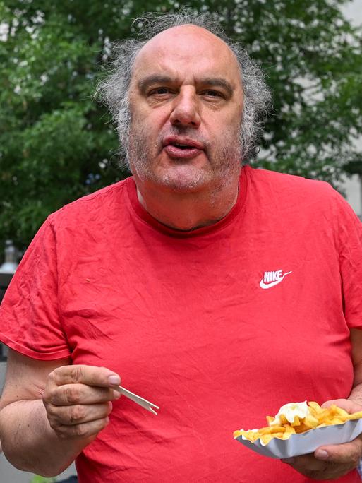 Matthias Lilienthal, der neue Intendant der Volksbühne, steht mit Pommes frites im Prater am Rande einer Pressekonferenz, wo er die Spielzeit 2026/27 der Volksbühne am Rosa-Luxemburg-Platz vorstellt.