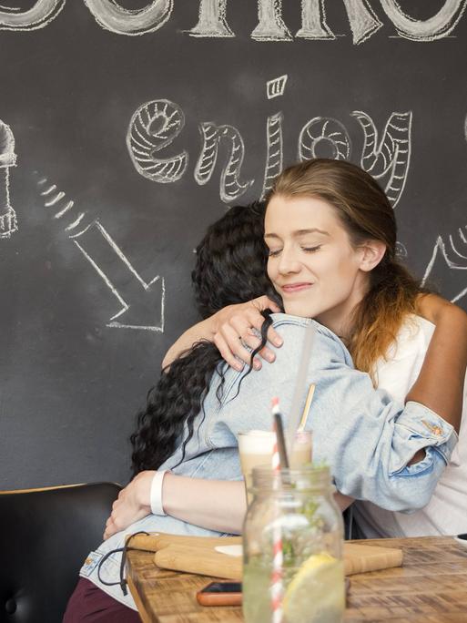 Zwei Freunde umarmen sich in einem Café 