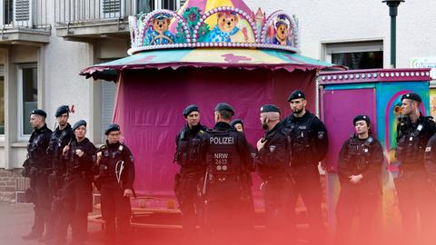 Polizisten stehen beim Besuch von Bundeskanzler Olaf Scholz (SPD) in Solingen vor einem geschlossenen Karussell Wache.