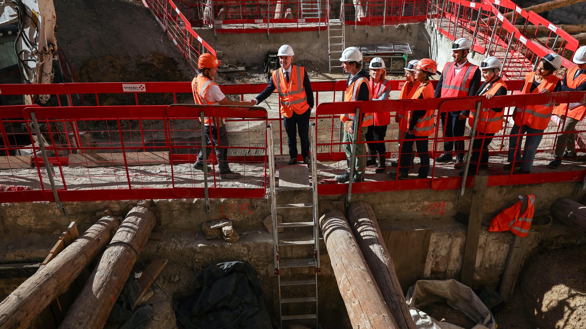Mehrere Menschen gehen in orangen Westen auf Laufstegen über eine Baustelle in Paris, wo das gallische Lutetia vermutet wird.
