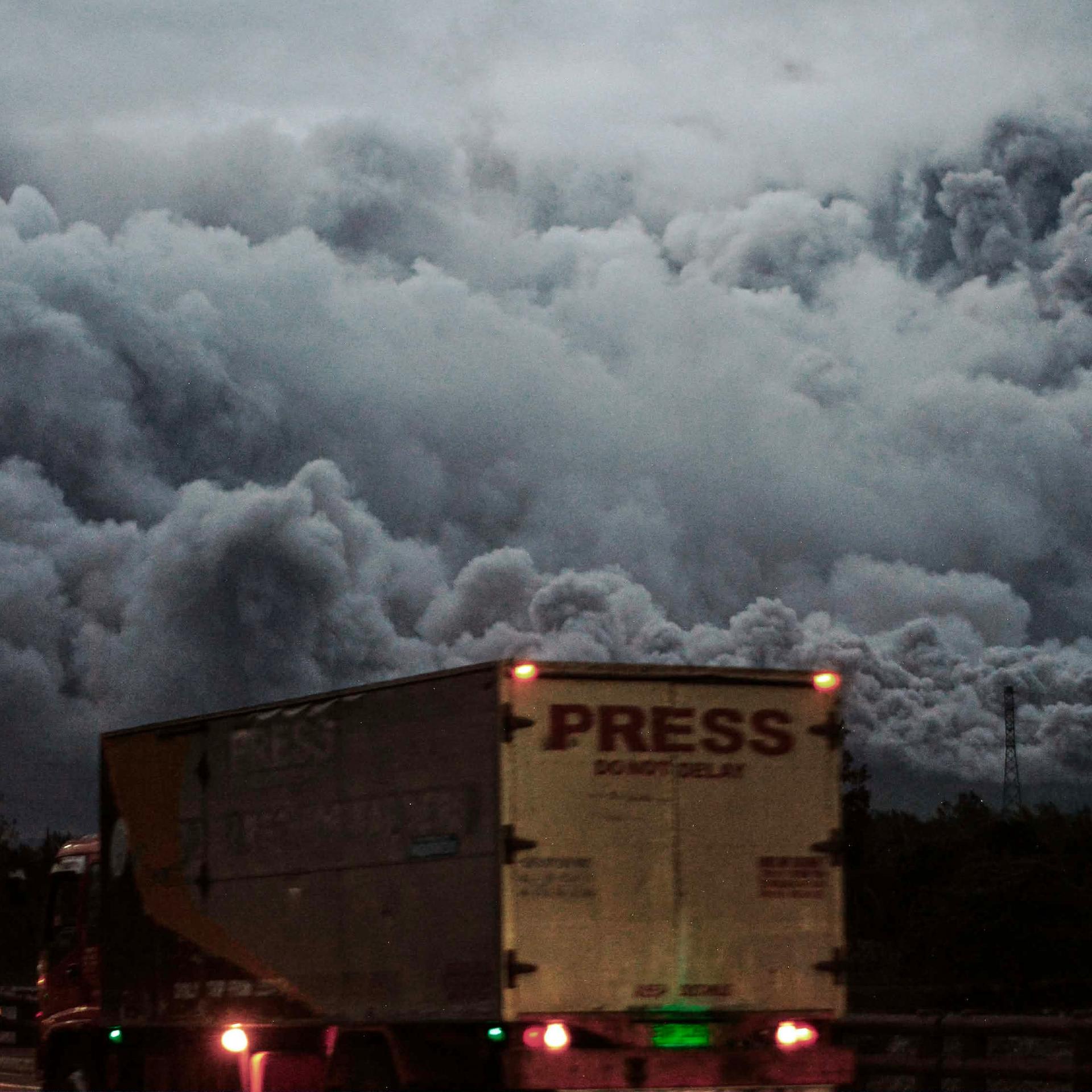 Philippinen, Daraga: Der Vulkan "Mayon" spuckt Asche, während Fahrzeuge in der Nähe vorbeifahren.
