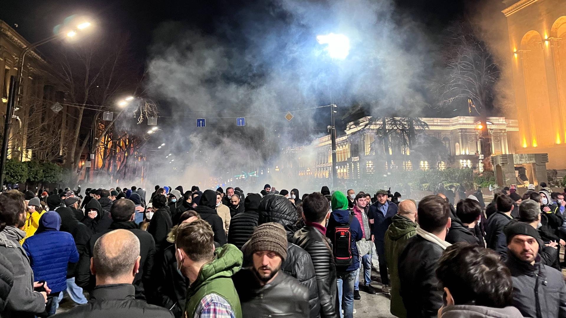 Zahlreiche Demonstranten haben sich in den Straßen von Tiflis versammelt, um zu protestieren. Im Hintergrund ist Tränengas der Polizei zu sehen.