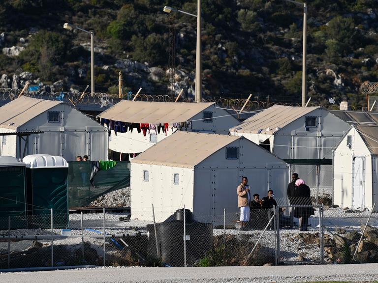 Mehrere provisorische Zelte stehen im Flüchtlingslager Moria auf der griechischen Insel Lesbos, vor einigen stehen Migranten. Mehrere provisorische Zelte stehen im Flüchtlingslager Moria auf der griechischen Insel Lesbos, vor einigen stehen Migranten.