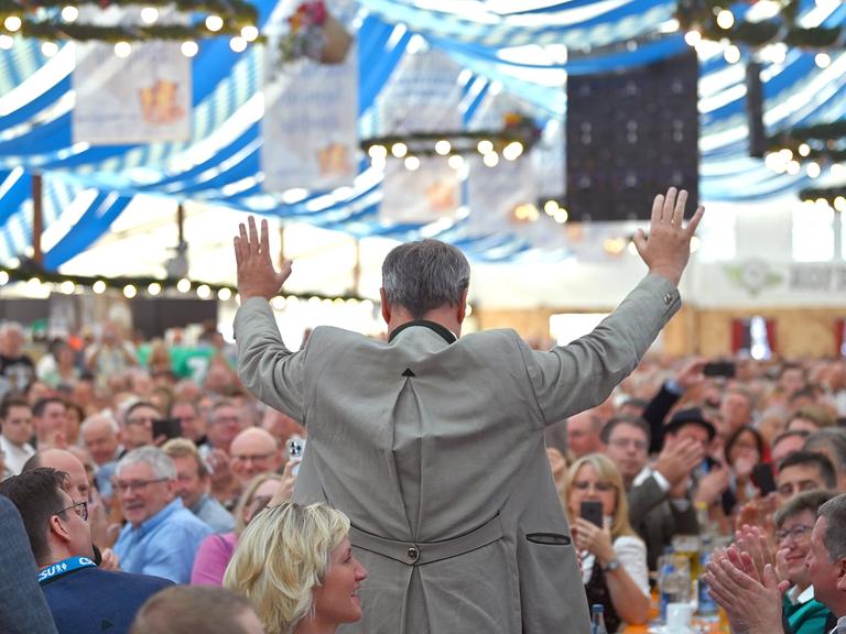 Der Ministerpräsident von Bayern, Markus Söder, lässt sich mit ausgebreiteten Armen in einem Bierzelt feiern.