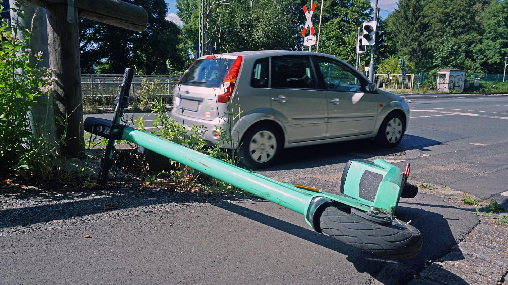 Ein sogenannter E-Scooter liegt umgeworfen auf einem Bürgersteig am Straßenrand. Ein sogenannter E-Scooter liegt umgeworfen auf einem Bürgersteig am Straßenrand.