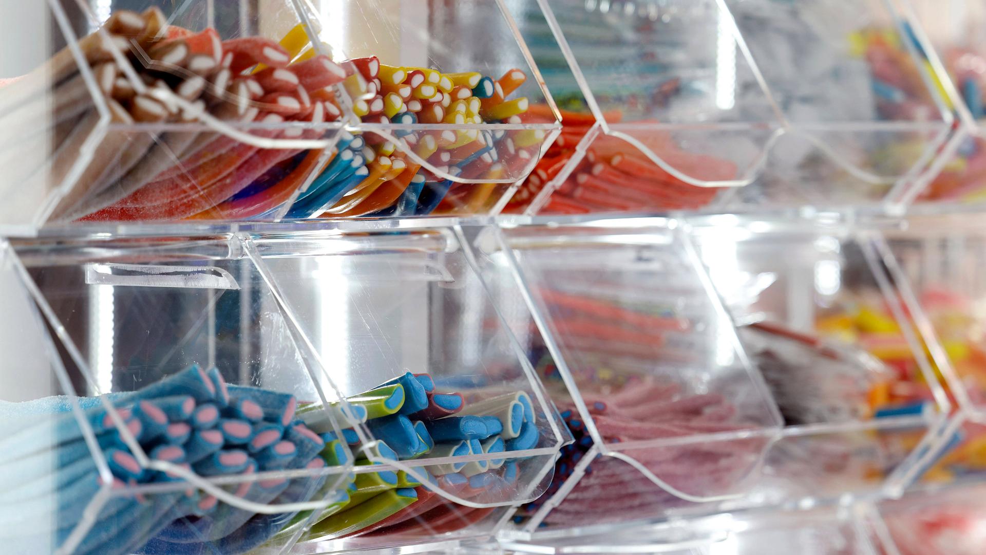 Das Bild zeigt mehrere Plastik-Schütten, in denen verschiedene Sorten von Fruchtgummis aufbewahrt sind.