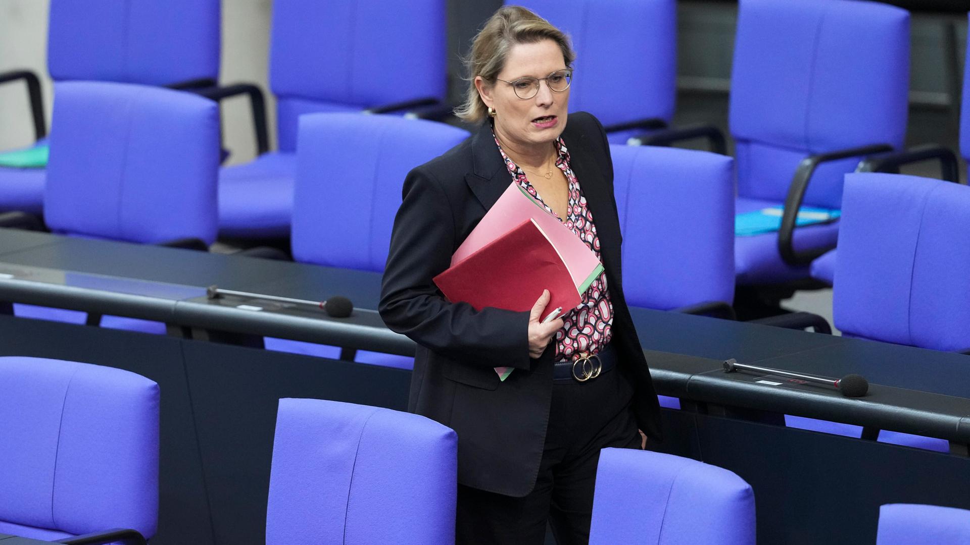 Dr. Stefanie Hubig, Bundesministerin der Justiz und für Verbraucherschutz läuft mit einer Mappe unter dem Arm durch eine Sitzreihe im Deutschen Bundestag