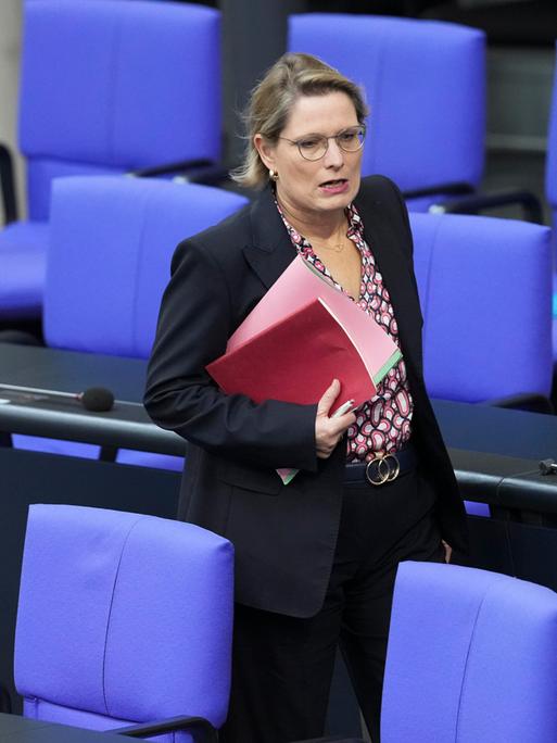 Dr. Stefanie Hubig, Bundesministerin der Justiz und für Verbraucherschutz läuft mit einer Mappe unter dem Arm durch eine Sitzreihe im Deutschen Bundestag Dr. Stefanie Hubig, Bundesministerin der Justiz und für Verbraucherschutz läuft mit einer Mappe unter dem Arm durch eine Sitzreihe im Deutschen Bundestag