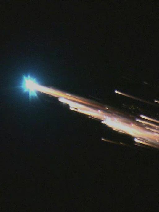 Eintritt eines Satelliten in die Erdatmosphäre, ein glühender Schweif ist am Nachthimmel zu sehen.