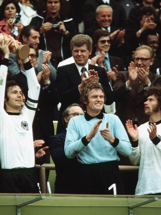 Franz Beckenbauer, Sepp Maier und Paul Breitner jubeln mit der Trophäe bei der Weltmeisterschaft 1974 in Deutschland
