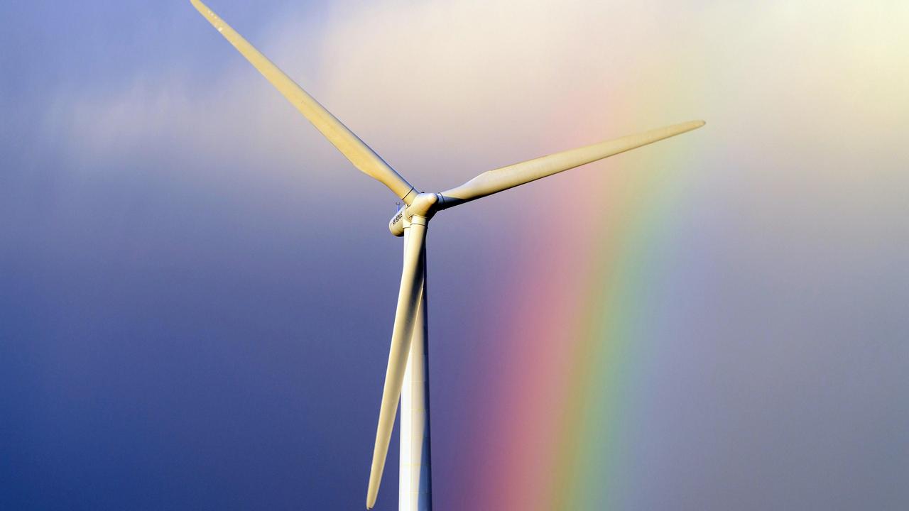 Ein Windkraftrad vor blauem Himmel und Regenbogen