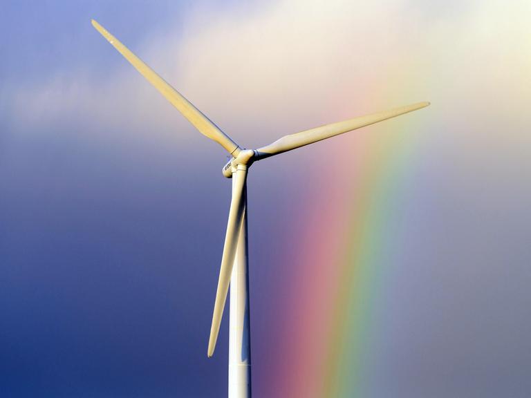 Ein Windkraftrad vor blauem Himmel und Regenbogen