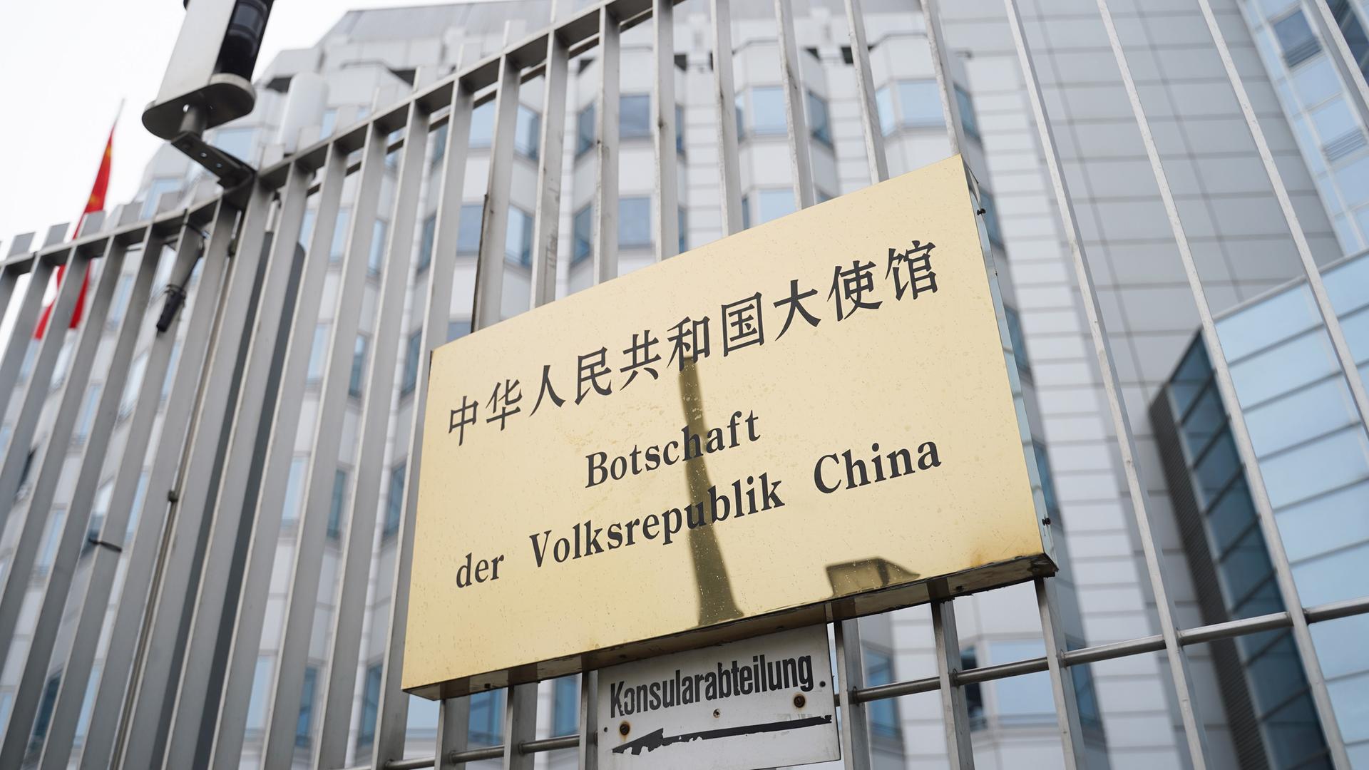 An einem Zaun ist ein Schild mit der Aufschrift "Botschaft der Volksrepublik China" befestigt. An einem Zaun ist ein Schild mit der Aufschrift "Botschaft der Volksrepublik China" befestigt.