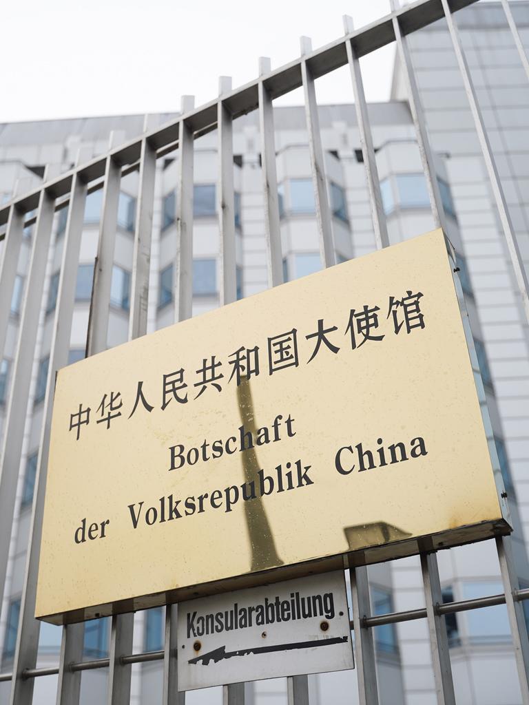 An einem Zaun ist ein Schild mit der Aufschrift "Botschaft der Volksrepublik China" befestigt.