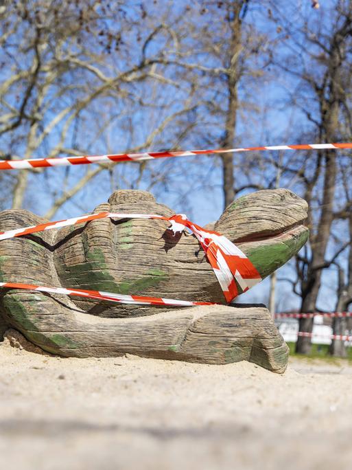 Geschlossener Spielplatz mit Holzkrokodil hinter Flatterband im Rosensteinpark Stuttgart als Auswirkungen der Corona-Krise im Februar 2022.