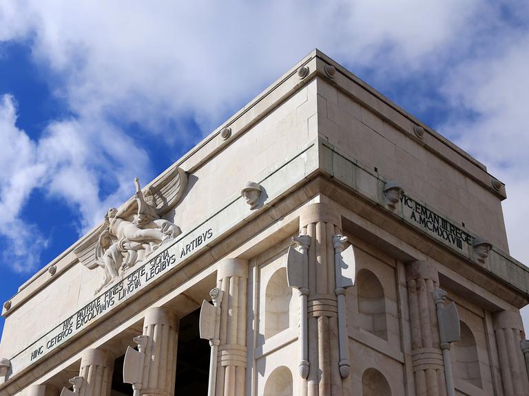 Das Siegesdenkmal in Bozen von unten aufgenommen vor blauem Himmel. 