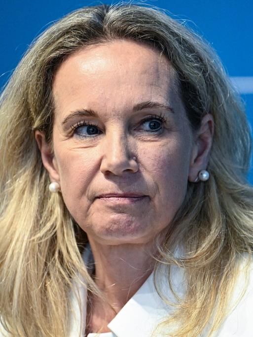 Sarah Wedl-Wilson sitzt auf einem Podium vor einer blauen Wand auf der "Berlin" steht