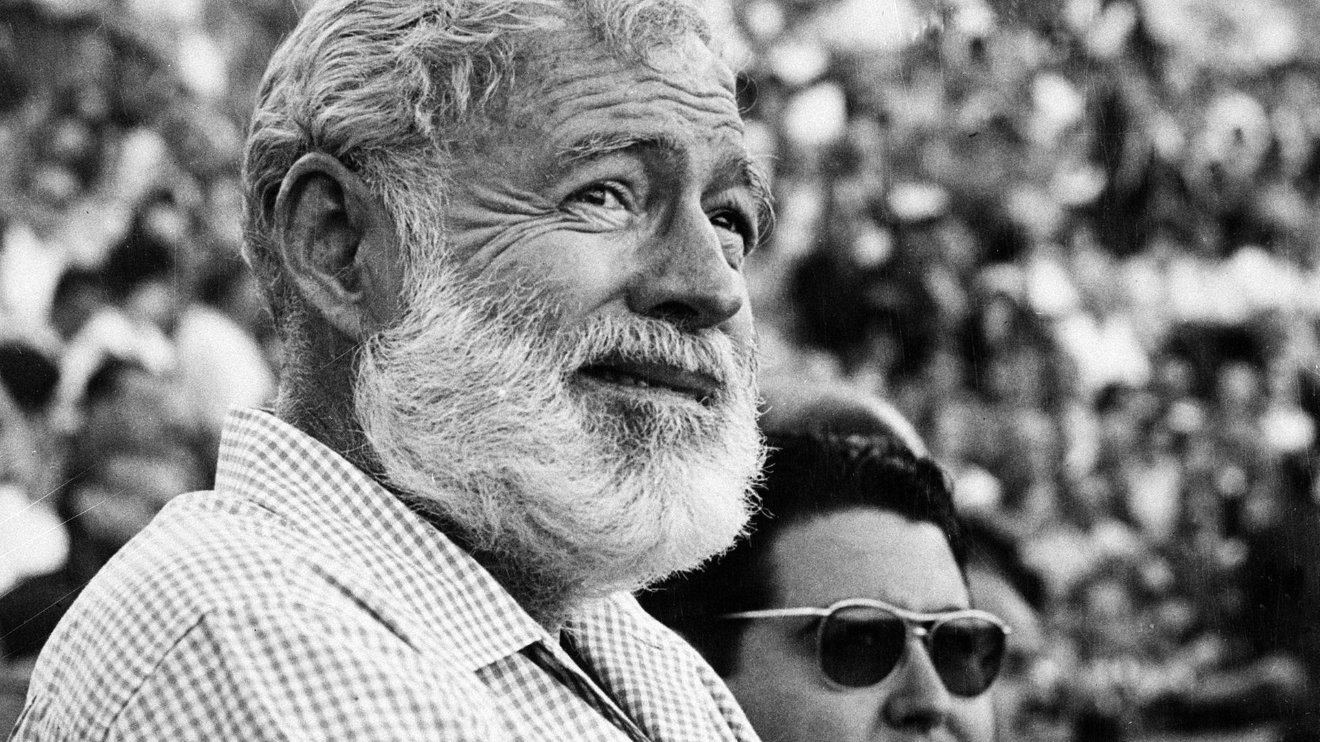 Schwarzweißporträt von Ernest Hemingway als älterem Mann in einem Stadion.
