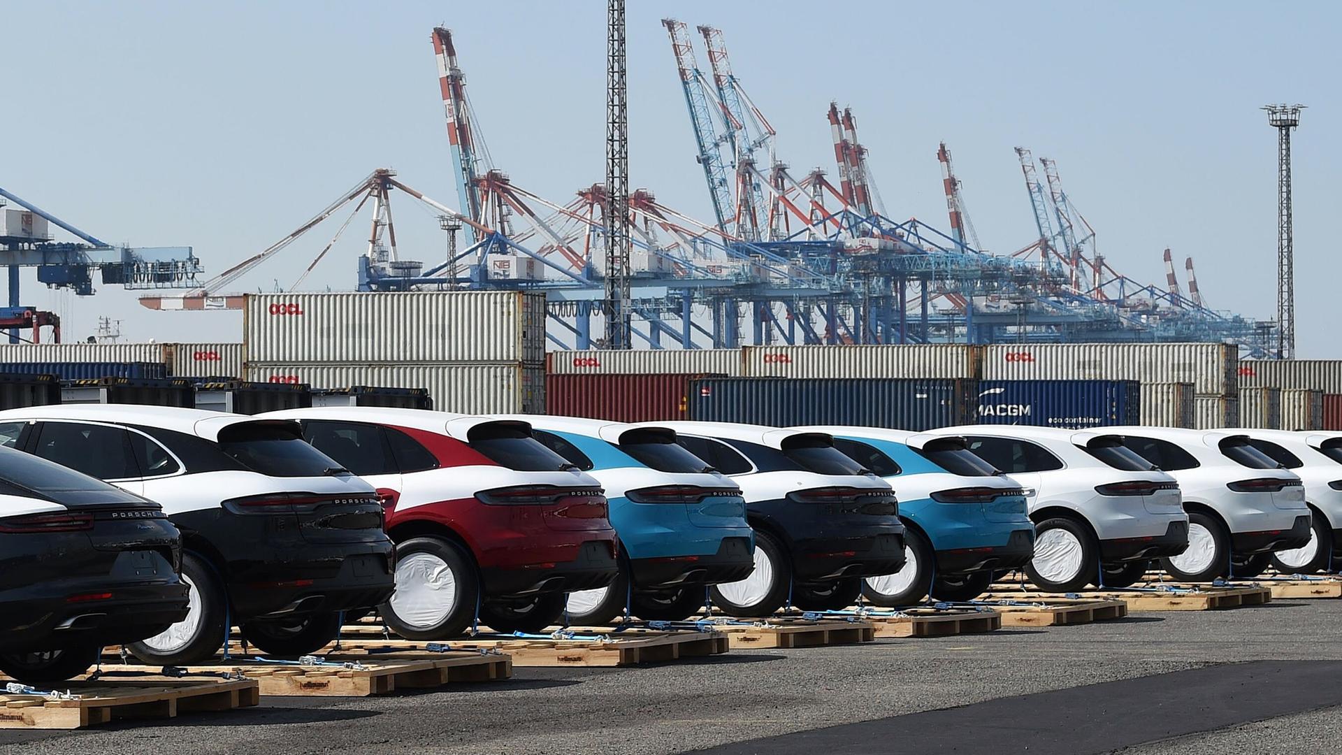 Porsche-Fahrzeuge stehen vor ihrer Verladung in Container auf Paletten im Hafen