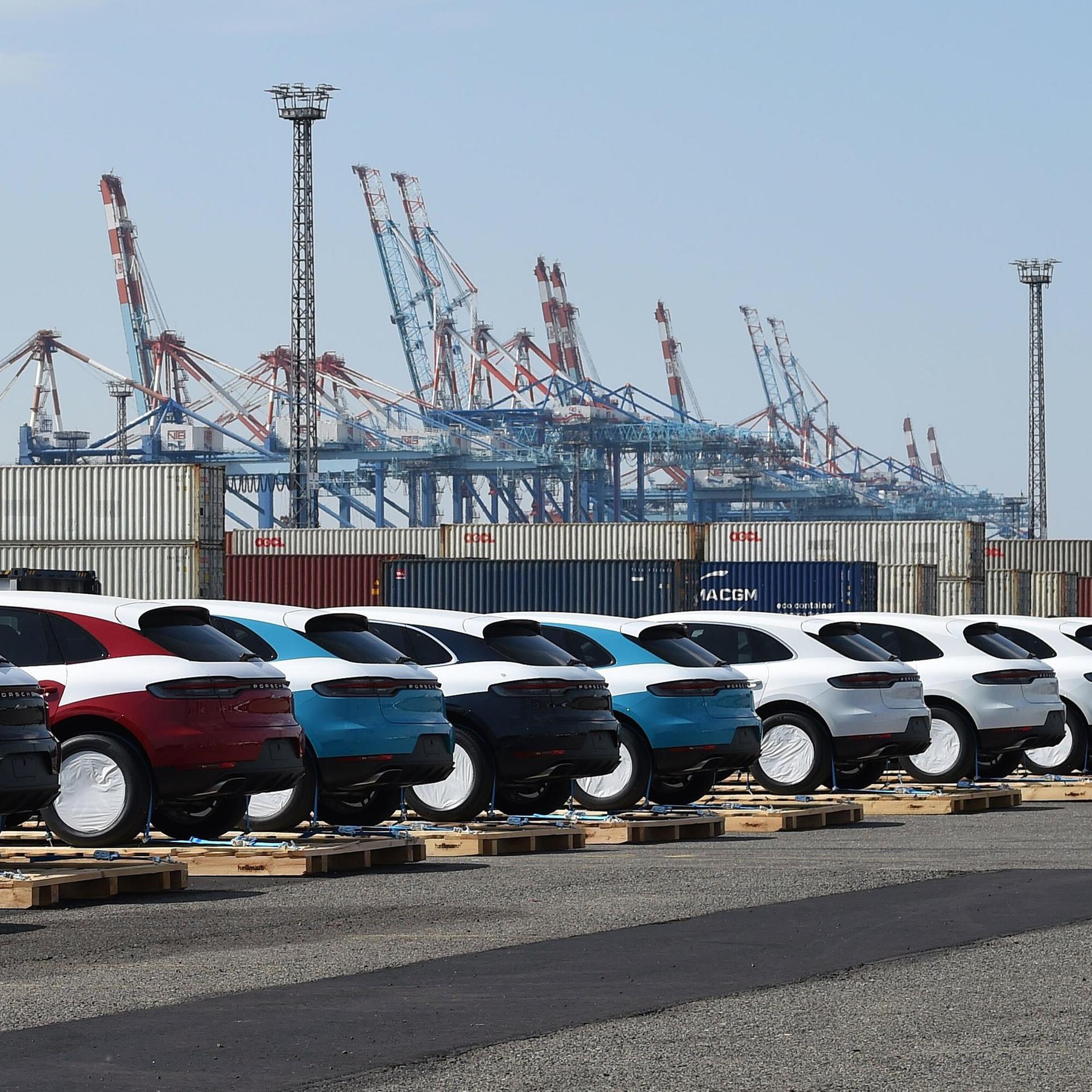 Porsche-Fahrzeuge stehen vor ihrer Verladung in Container auf Paletten im Hafen