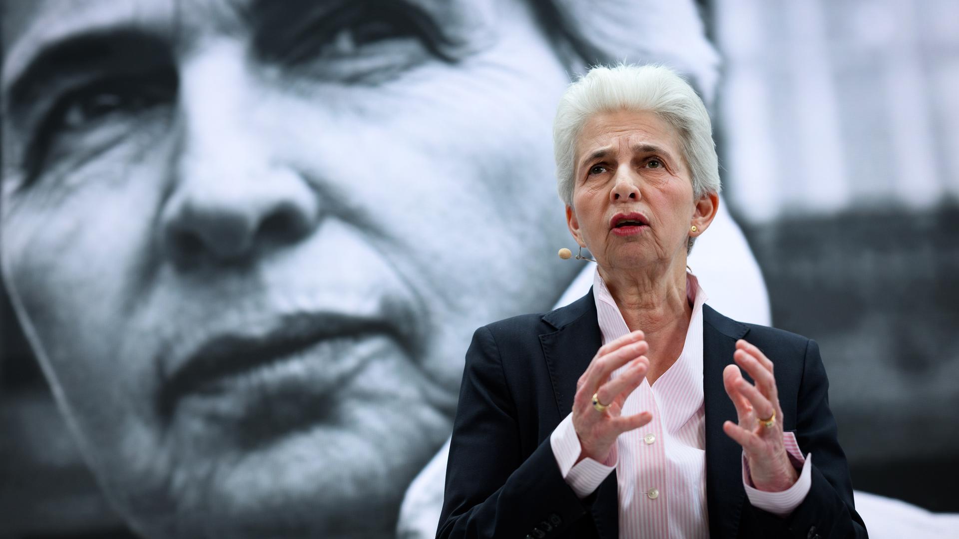 Marie-Agnes Strack-Zimmermann (FDP) steht im Hans-Dietrich-Genscher-Haus und hält eine Rede. Sie gestikuliert mit ihren Händen. Im Hintergrund ist ein Wahlplakat mit ihrem Konterfei zu erkennen. 