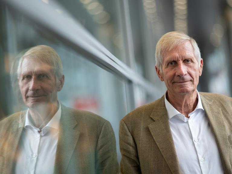 Ulrich Wickert, Journalist und Autor, steht an eine Wand gelehnt.